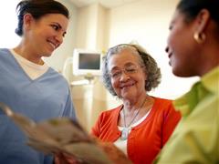banner-image-07 Older black woman and her daughter talking with a nurse in a hospital setting.
