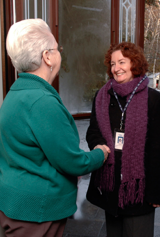 client-educator Home Service Representative from Lifeline shaking hands with a client in their home.